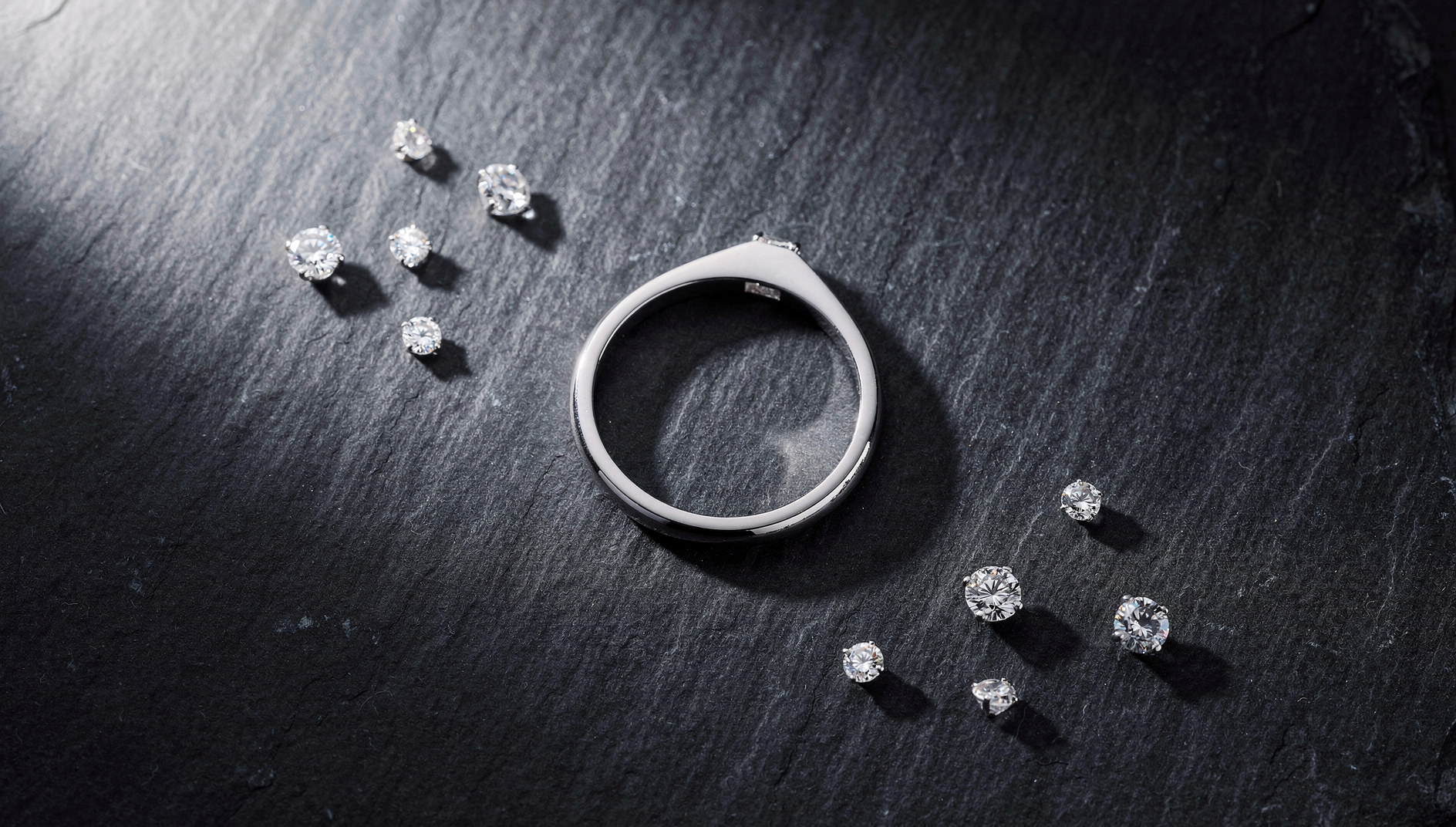Close-up of a platinum ring on dark slate surface with soft luxury lighting