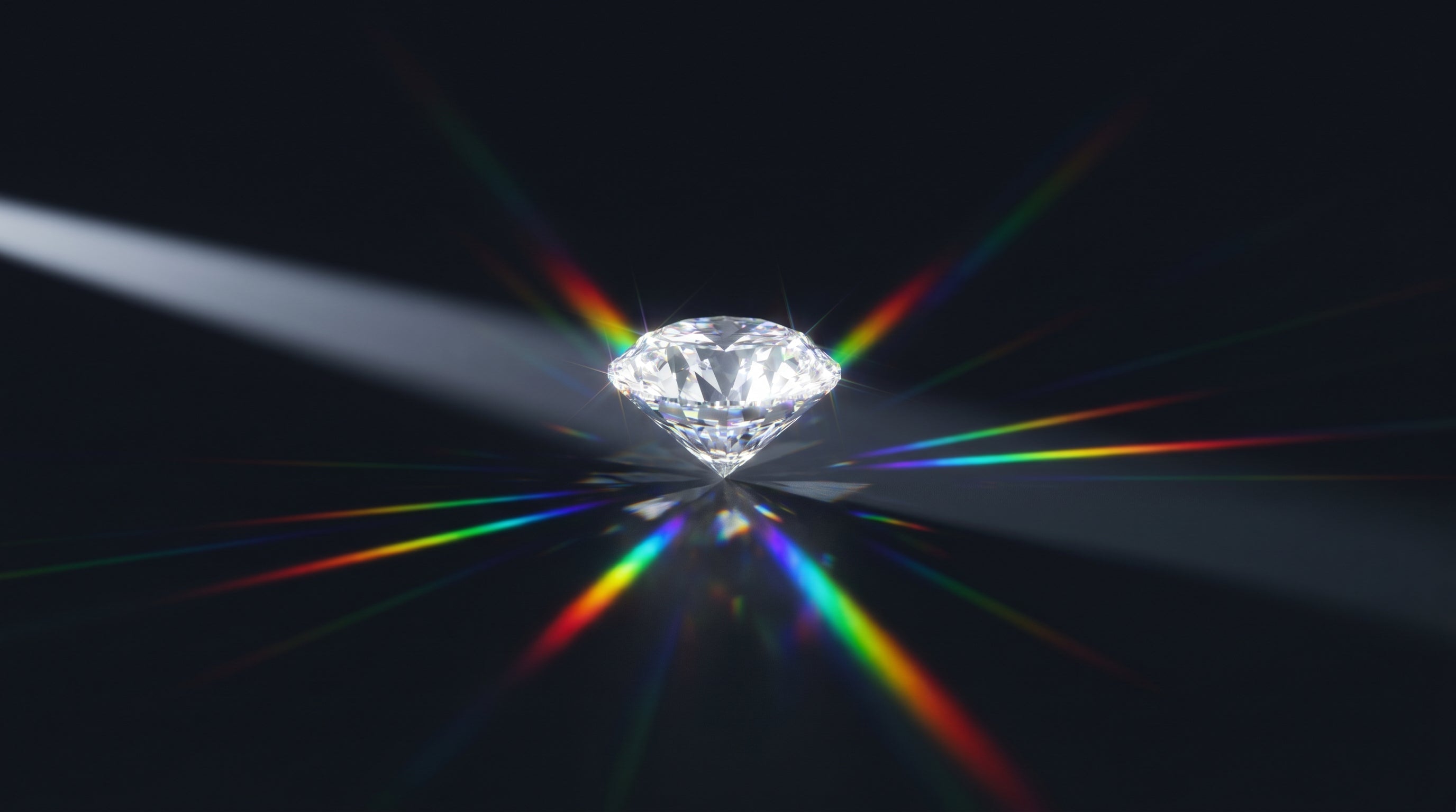 Faceted gemstone splitting a beam of light into rainbow spectral flashes, showing fire and brilliance against a dark background