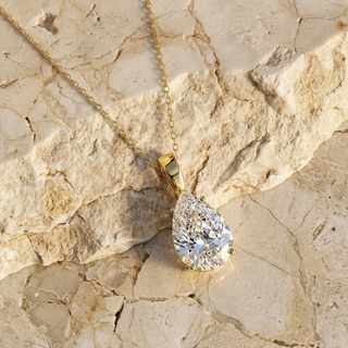 Goccia pear diamond solitaire pendant in gold worn at the collarbone