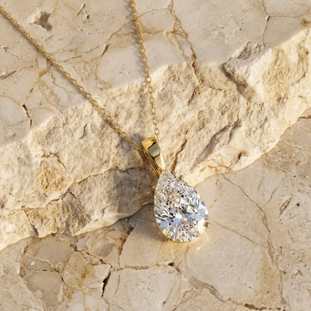 Goccia pear diamond solitaire pendant in gold worn at the collarbone